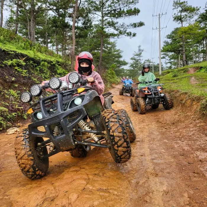 a group riding atvs down a muddy track.