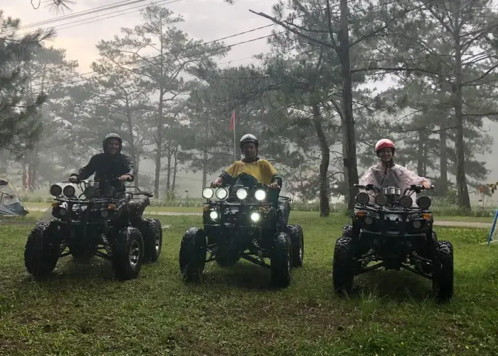 three people on atvs smiling in the rain.