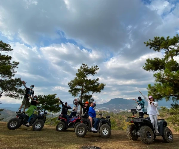 a group standing on atvs for a photo ontop of a hill.